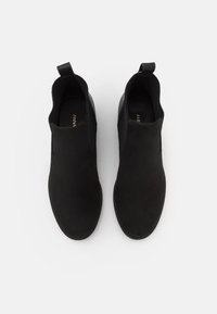 Black ankle boots made of suede with elastic side panels and pull tabs. Smooth texture, rounded toe, minimalist design.