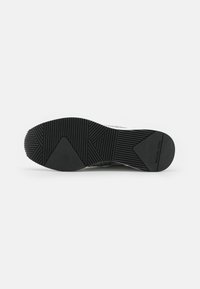 Suola di scarpa in materiale gomma nera, con una presa texturizzata e a motivo. Include il marchio "MICHAEL KORS" sul lato.