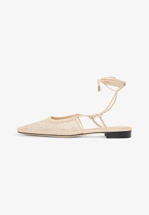 Litte beige-kengät, joissa on terävä kärki, nauhakuosi ja hopeiset niitit. Varustettu nilkkastrapilla ja matalalla mustalla korolla.