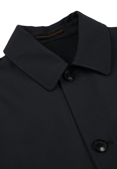 Zwarte overhemd met knopen en een gestructureerde kraag, met een ribbelstructuur en een enkele knoopdetail bij de kraag.