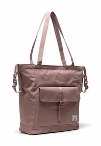 Sac fourre-tout rectangulaire mauve avec longues poignées, poche avant à rabat avec boucle, et petite étiquette de marque dans le coin inférieur droit.