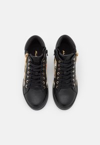 Černé kožené tenisky se zlatými doplňky, zdobené květinovými vzory, s předními tkaničkami a postranními zipy. Texturovaný materiál.