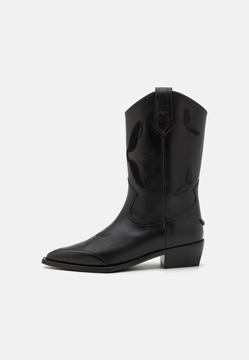 Juodos odos kaubojiški botas su smailiu pirštu, siuvinėtais akcentais ir žemu kulnu. Yra vertikalus siuvimas ir šoninės traukimo juostos.