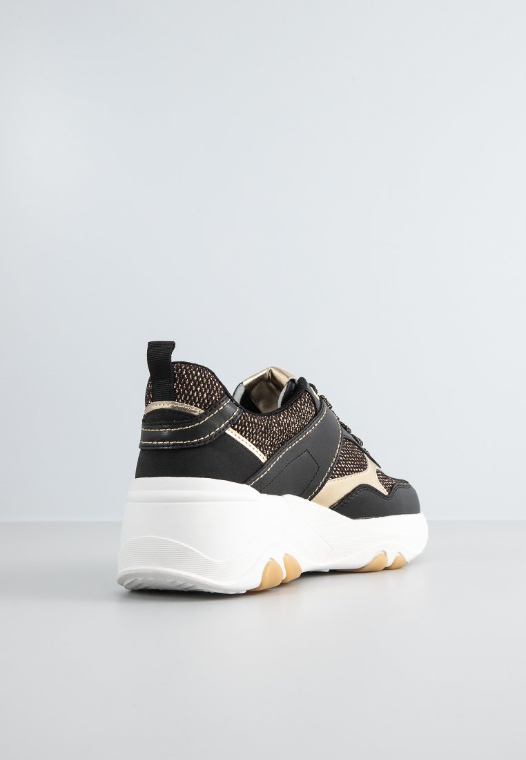 Sneaker neri e oro con tomaia in rete, suola bianca spessa e texture a contrasto. Design slip-on con linguetta sul tallone.
