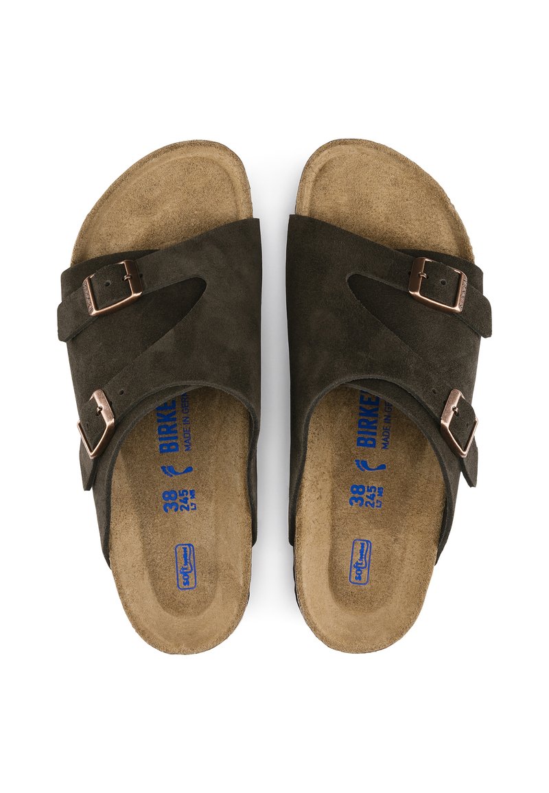 Sandales en suede marron foncé avec deux boucles ajustables, semelle intérieure en liège ergonomique et étiquette de taille bleue à l'intérieur. Texture lisse et design ouvert.