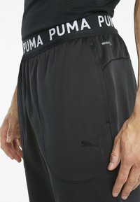 Schwarze Sportshorts mit einem elastischen Bund und weißem "PUMA"-Logo. Weicher Stoff, Seitentaschen und ein dezentes schwarzes Logodetail.