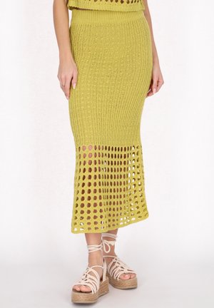 Strikket midi-nederdel i olivengrøn med ribbet top og åben, rund hækling mønster i kanten. Parret med beige espadrille-sandaler.