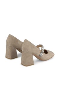 Tacchi alti in suede beige con punta triangolare e tacco quadrato. Presentano una fascia decorativa con pietre rhinestone trasparenti sul collo del piede.