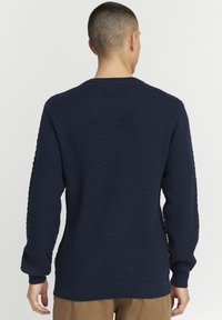 Pulover tricotat navy cu un model texturat în raion de fagure, gât rotund, manșete și tiv cu model în relief, având mâneci lungi și o croială confortabilă.