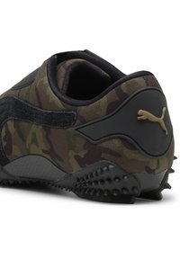 Πίσω πλευρά του μαύρου και πράσινου καμουφλάζ πάνινο παπούτσι Puma με υφασμάτινη σόλα και χρυσό λογότυπο Puma στην ταμπέλα της φτέρνας.