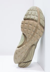 Sole tenisky v krémové a světle hnědé barvě s texturovaným vzorem pro lepší uchopení, zakřiveným designem a zesílenými detaily pro zvýšenou odolnost.