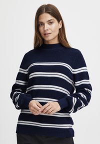 Marineblauer Strickpullover mit weißen horizontalen Streifen, hohem Kragen und gerippten Bündchen. Strukturierte Passform mit einem strukturierten Stoff.