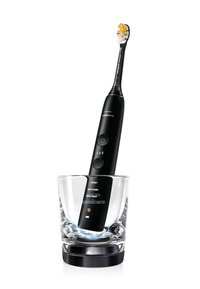 Brosse à dents électrique Philips Sonicare noire se tenant dans un gobelet de charge en verre avec une base illuminée sur fond blanc.