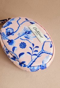 Rund fodral med blommönster, ljusrosa bakgrund och blått mönster. Har en textilstruktur och en vit logotags.