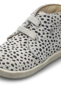 Zapato gris con patrón de puntos negros, diseño de cordones, puntera redonda y suela de goma texturizada. Presenta un acento metálico en el costado.