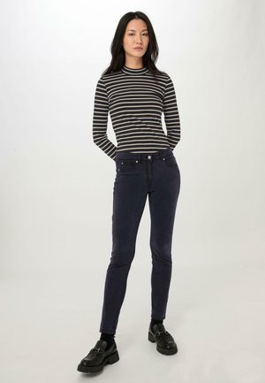 Zwart en crèmekleurig gestreept langmouwen shirt, gecombineerd met donkerblauwe skinny jeans met vijf zakken en een slim fit ontwerp. Zwarte schoenen maken de look compleet.