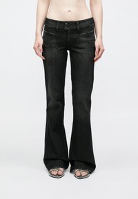 Mustad lehvitatud teksad denimist, mis on varustatud kahe esitasku, detailselt õmmeldud ja keskmise kõrgusega vöökohaga, millel on kaks nööpi.