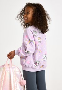 Lila Sweatshirt mit Cartoon-Tieren und pastellfarbenen Akzenten, runder Ausschnitt und gerippte Bündchen, kombiniert mit einem glänzenden rosa Rucksack.