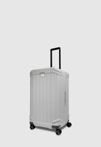 White hard-shell suitcase with vertical ridges, retractable black handle, four black wheels, and a side handle for easy carrying.