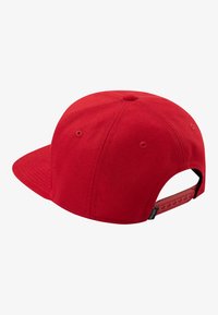 Red cap with a flat brim, made of textured fabric. Features a plastic adjustable strap at the rear and ventilation holes on the sides.
