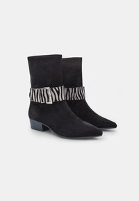 Mustmustest kingad, millel on terav nina ja plokk-kand, sisaldavad sääreosa, millel on zebra triibuline kangast riba koos hõbedase pandlaga.