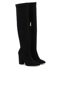 Black knee-high boots made of suede, featuring a pointed toe, block heel, and a side zipper with gold hardware. Smooth texture.