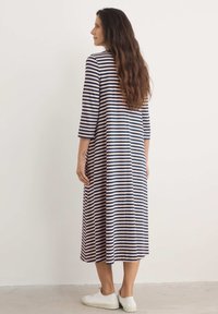 Pruhované midi šaty v námořnické modři a světlé růžové, s volným střihem, tříčtvrtečním rukávem a kombinované s bílými teniskami.