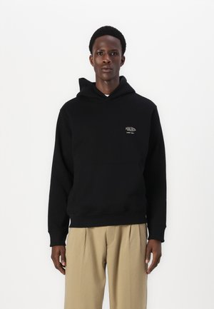 Black hooded sweatshirt with front pocket and ribbed cuffs. Features small logo on chest. Material appears soft and textured.