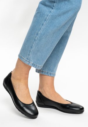 Schwarze Ballettflats aus Leder mit abgerundetem Zehenbereich und niedrigem Absatz, mit glatter Textur und minimalistischem Design, kombiniert mit hellblauen, knöchellangen Jeans.
