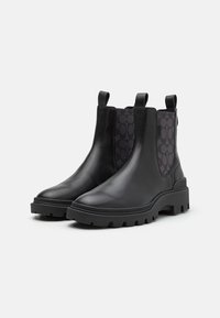 Schwarze Leder-Chelsea-Stiefel mit einer strukturierten schwarzen Stoffeinlage mit Logo-Muster, robuster Gummisohle und Anzieh-Schlaufen.