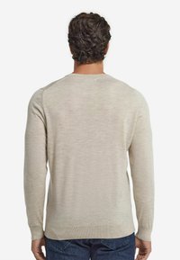 Ljusbeige långärmad tröja med rund hals, ribbade ärmslut och nederkant, gjord av mjukt tyg, med en slät textur och figurnära design.