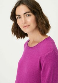 Fuchsiafarbener Strickpullover mit rundem Ausschnitt und kurzen Ärmeln, mit einer weichen Textur und dezenten Stickdetails entlang des Kragens.