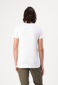 Hvid kortærmet t-shirt, lavet af glat bomuld, med rund halsudskæring og lige kant. Ingen mønstre eller accenter synlige.