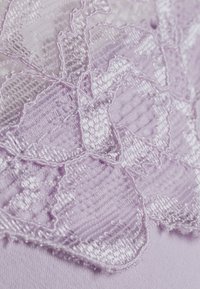 Tessuto in pizzo lavanda con motivi floreali dai dettagli intricati e una texture liscia, sovrapposto a un materiale lavanda morbido e uniforme.