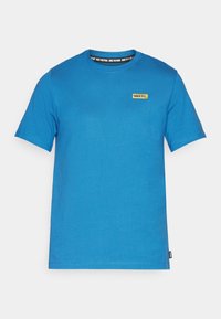 Camiseta de algodón azul con cuello redondo, mangas cortas y un pequeño logo amarillo "NIKE F.C." en el lado izquierdo del pecho. Diseño sencillo, sin patrones.