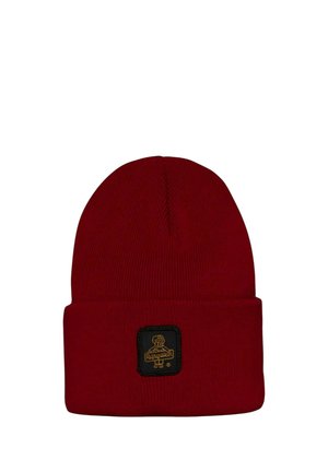 Berretto rosso lavorato a maglia con risvolto e una piccola toppa nera con un logo giallo di un cane e testo.