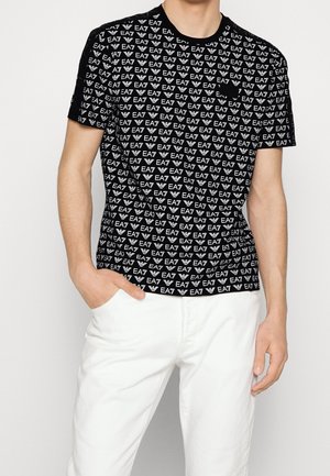 T-shirt nera a maniche corte con motivo ripetuto del logo EA7 bianco. Girocollo a costine e vestibilità comoda. Abbinata a pantaloni bianchi.
