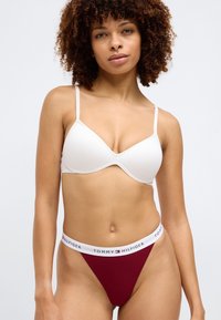 Hvit trådløs BH med justerbare stropper, kombinert med mørkerød truse med hvit merkevare midjebånd. Glatt stoff, enkelt design.