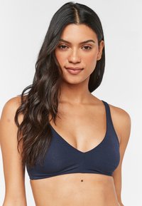 Marineblaue Bralette mit V-Ausschnitt, aus weichem Stoff gefertigt, mit nahtlosem Finish und dünnen Trägern. Keine sichtbaren Befestigungen oder Muster.