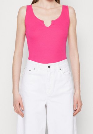 Body fucsia senza maniche con scollo a V, abbinato a jeans bianchi a vita alta. Tessuto morbido e elasticizzato con una forma aderente.