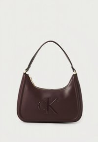 Bolso de mano de cuero burdeos con forma curva, un asa superior única, logotipo "CK" en relieve y cierre de cremallera en la parte superior.