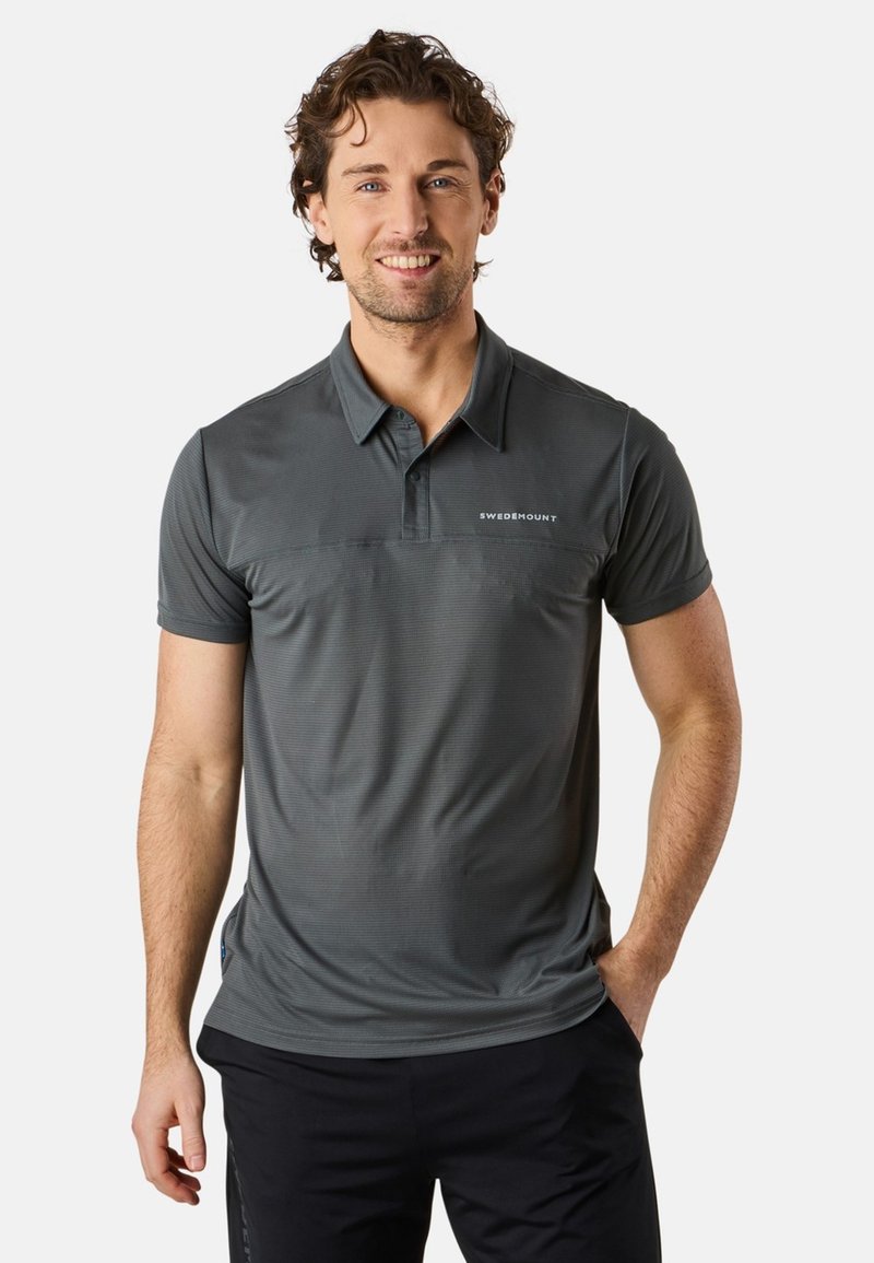 Grå pikétröja med en texturerad yta, korta ärmar, en krage och en logotyp fram. Kombinerad med mörka byxor för en avslappnad stil.