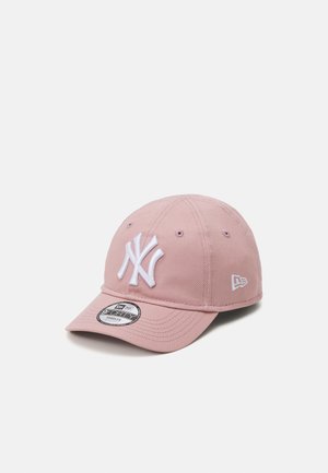 Pink baseball cap made of cotton with a curved brim. Features a white embroidered logo and eyelets for ventilation. Brand logo on the side.