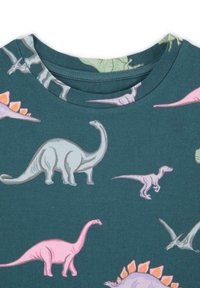 Krátký rukáv tričko v teal látce s barevnými potisky dinosaurů, včetně brontosaurů, stegosaura a vzorů velociraptora.