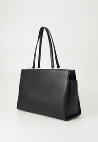 Svart skinnhåndbag med en strukturert form, romslig design og to lange håndtak. Har en jevn tekstur og minimalistisk stil.