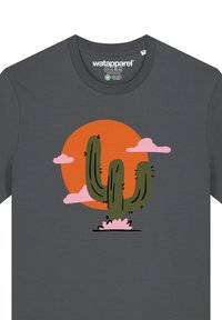 T-shirt gris présentant un graphique d'un cactus vert avec des accents noirs, entouré d'un nuage rose et d'un soleil orange.