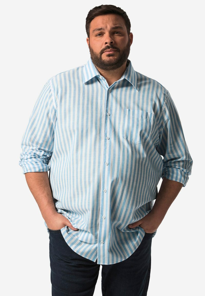 Ljust blå och vitrandig skjorta med knäppning, långa ärmar, en ficka på vänster bröst och rundad nederkant. Buren med mörka jeans.