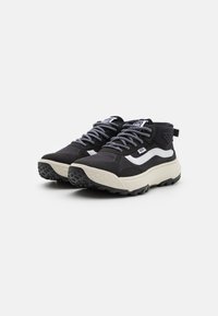 Black athletic shoes with a textured rubber sole, white stripe accents, and patterned black-and-white laces. Features ankle support and breathable material.