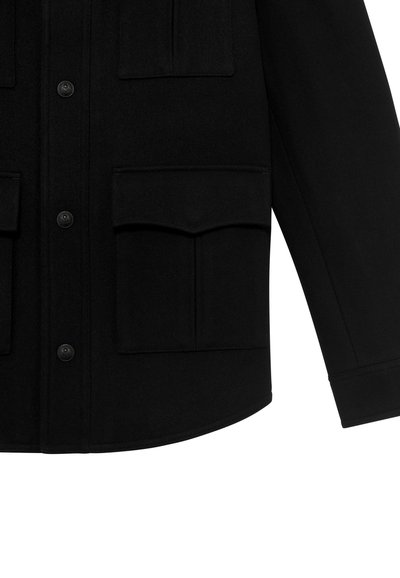 Giacca nera con chiusura a bottone, tasche piatte e una vestibilità strutturata. Realizzata in un tessuto testurizzato con un design pulito e minimale.