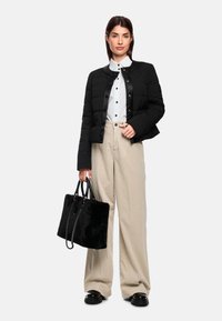 Black quilted jacket, white collared shirt, beige wide-leg pants, and a black faux fur tote bag with chain accents. Black platform shoes complete the look.